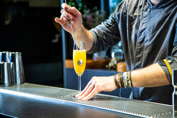 Barman prepara cokctail mimosa sobre la barra de un cocktail bar nocturno exclusivo muy delicioso