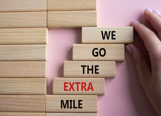We go the extra mile symbol. Wooden blocks with words We go the extra mile. Beautiful pink...