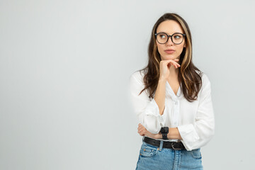 A contemplative young woman with long hair and glasses rests her chin on her hand