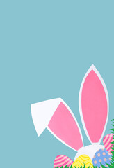 Easter background with rabbit ears and eggs on a blue background. Easter concept. Copy space.
