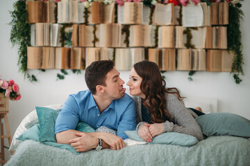 A couple in love is lying on the bed. The heads are turned towards each other. The man sticks out...
