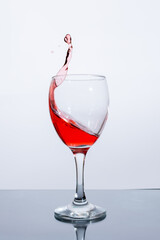 Splashes of red wine in a glass on a white background