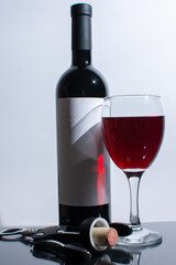 Glass of red wine near bottle and corkscrew