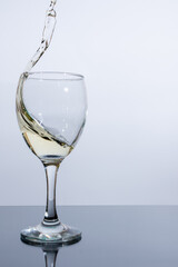 Splashes of light wine in a glass on a white background