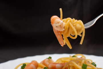 Spaghetti with shrimps and green onions on a fork