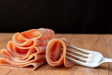 Thin slices of raw bacon on a fork