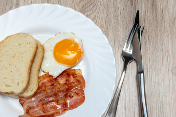 Fried egg with bacon and bread on a plate. English Breakfast