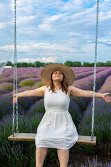 Woman in white dress riding on swing in lavender