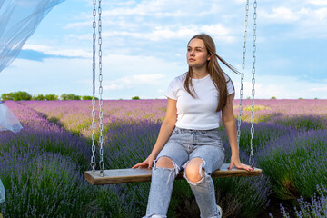 Cute girl sitting on a swing in a lavender field