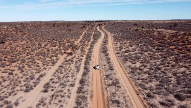Drone flight over Kalahari. Drone follows a tiny little car driving through a sandy gravel road in Namibia.