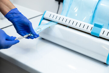 Dentist hands in blue gloves holding dentist tools using sterilizing box