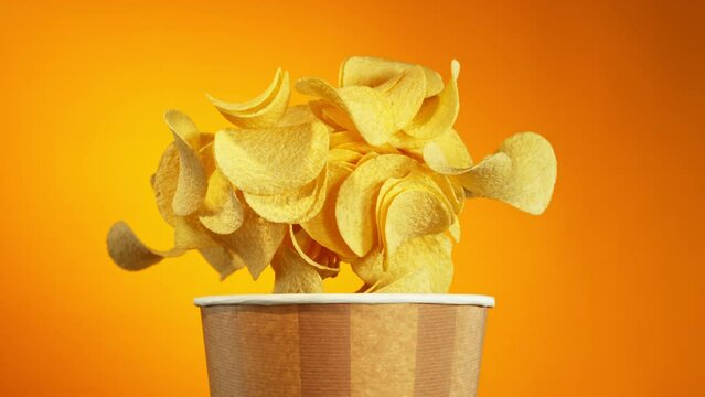 Super Slow Motion of Flying Fried Potatoes Chips for Bucket. Isolated on Colored Background. Filmed on High Speed Cinema Camera, 1000 fps.