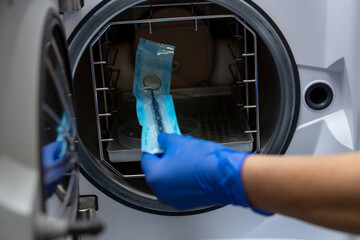 Dentist hands in blue gloves holding dentist tools doing sterilization of instruments
