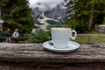 A cup of Italian cappuccino with Lake Pragser Wildsee in the background