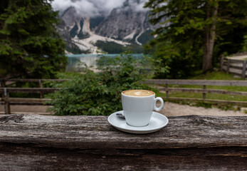 A cup of Italian cappuccino with Lake Pragser Wildsee in the background