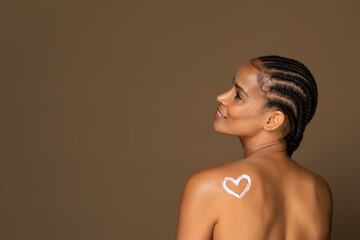 Black middle aged woman with heart-shaped lotion on back, free space