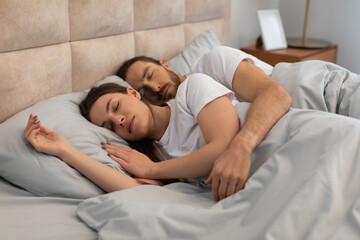 Young couple sleeping together in comfortable bed
