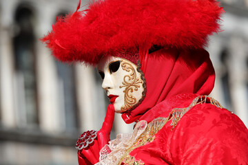 masked person with gloved hand during the Venice carnival with ancient palace in the background