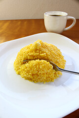 Brazilian breakfast. Couscous corn with a fork and a coffee cup.