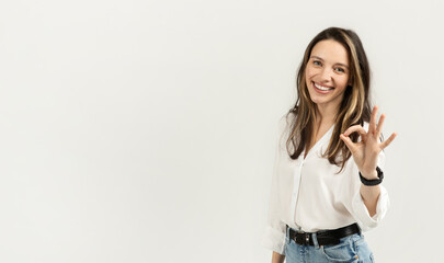 Bright and cheerful young woman with long hair giving a perfect gesture with her hand
