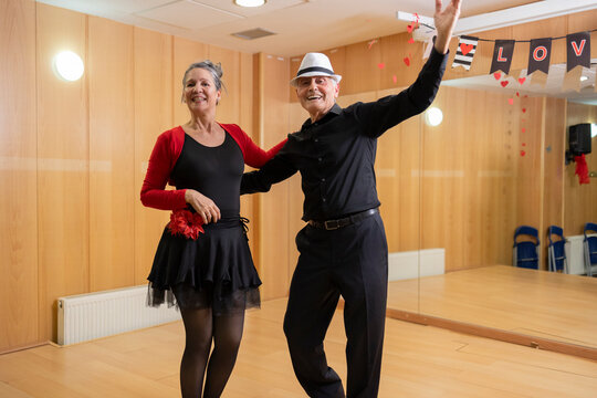 two middleaged older couple dancing in a hall with light strings