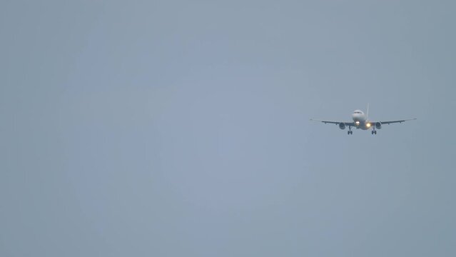 Jet plane with unrecognizable livery in the sky, approaching landing, long shot