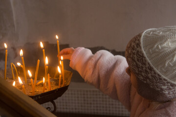 A child lights candles in prayer to the Lord in the chapel