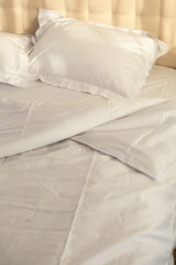 crumpled white bed linen morning routine in sunlight