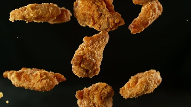 Super slow motion of flying fried chicken pieces with french fries and cola drink. Filmed on high speed cinema camera, 1000fps, placed on high speed cine bot. Camera in motion, following objects.