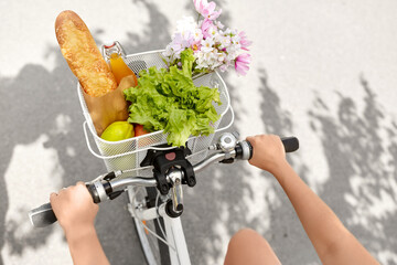 people, leisure and lifestyle - close up of woman with food and flowers in basket of bicycle on city street - 746072423