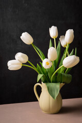 A bouquet of white tulips in a yellow jug
