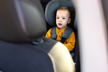 Boy sitting in safety car booster seat. Family and childhood journey concepts.