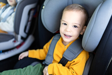 Boy sitting in safety car booster seat. Family and childhood travel concepts.