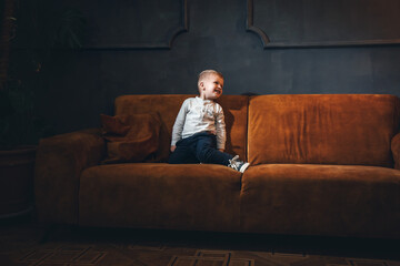 Adorable Handsome Little Cute Boy on Vintage Sofa in Dark Interior - 746081840