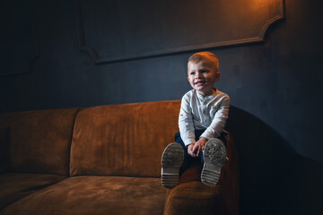 Adorable Little Cute Boy on Vintage Sofa in Dark Interior - 746081862