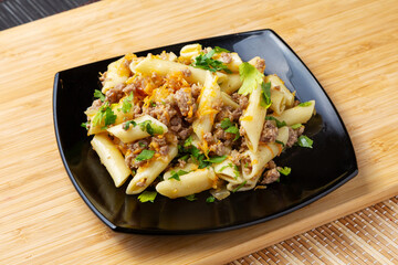 Pasta with minced meat on a wooden board.