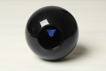 Magic eight ball with prediction Looks Like Yes on white table
