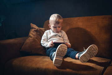Handsome Little Rich Boy with Smartphone Sitting in Dark Interior - 746082250