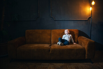 Adorable Little Cute Boy on Vintage Sofa in Dark Interior - 746082284