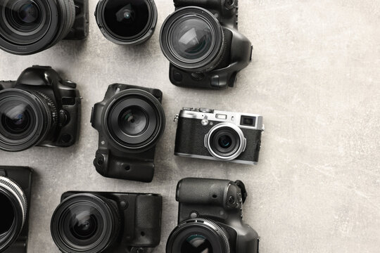 Modern cameras on gray textured table, flat lay. Space for text