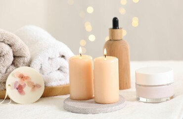 Fototapeta na wymiar Spa composition. Burning candles and personal care products on soft white surface