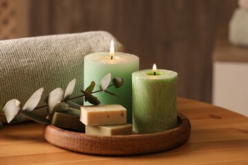 Spa composition. Burning candles, soap, towel and eucalyptus branch on wooden table