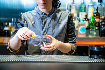 Camarera de cocktail bar prepara bloody Mary sobre una barra de un cocktail bar exclusivo en ambiente nocturno con detalle sobre el cocktail exquisito