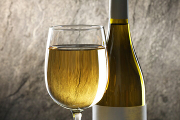 White wine in glass and bottle against grey background, closeup