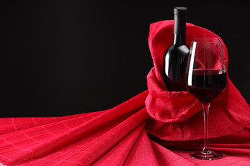 Stylish presentation of delicious red wine in bottle and glass on black background. Space for text
