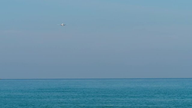 Airplane approaching to landing. Airliner flies over the blue sea. Plane in the sky