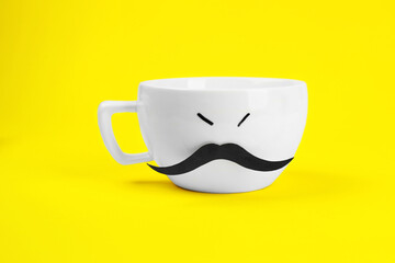 Man's face made of cup and fake mustache on yellow background