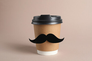 Paper cup of drink with fake mustache on grey background