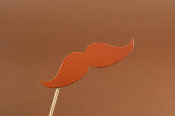 Fake paper mustache party prop on light brown background