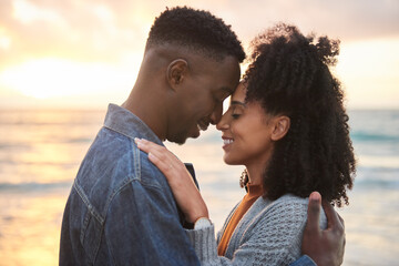 Loving multiethnic couple with closed eyes standing on a beach at dusk